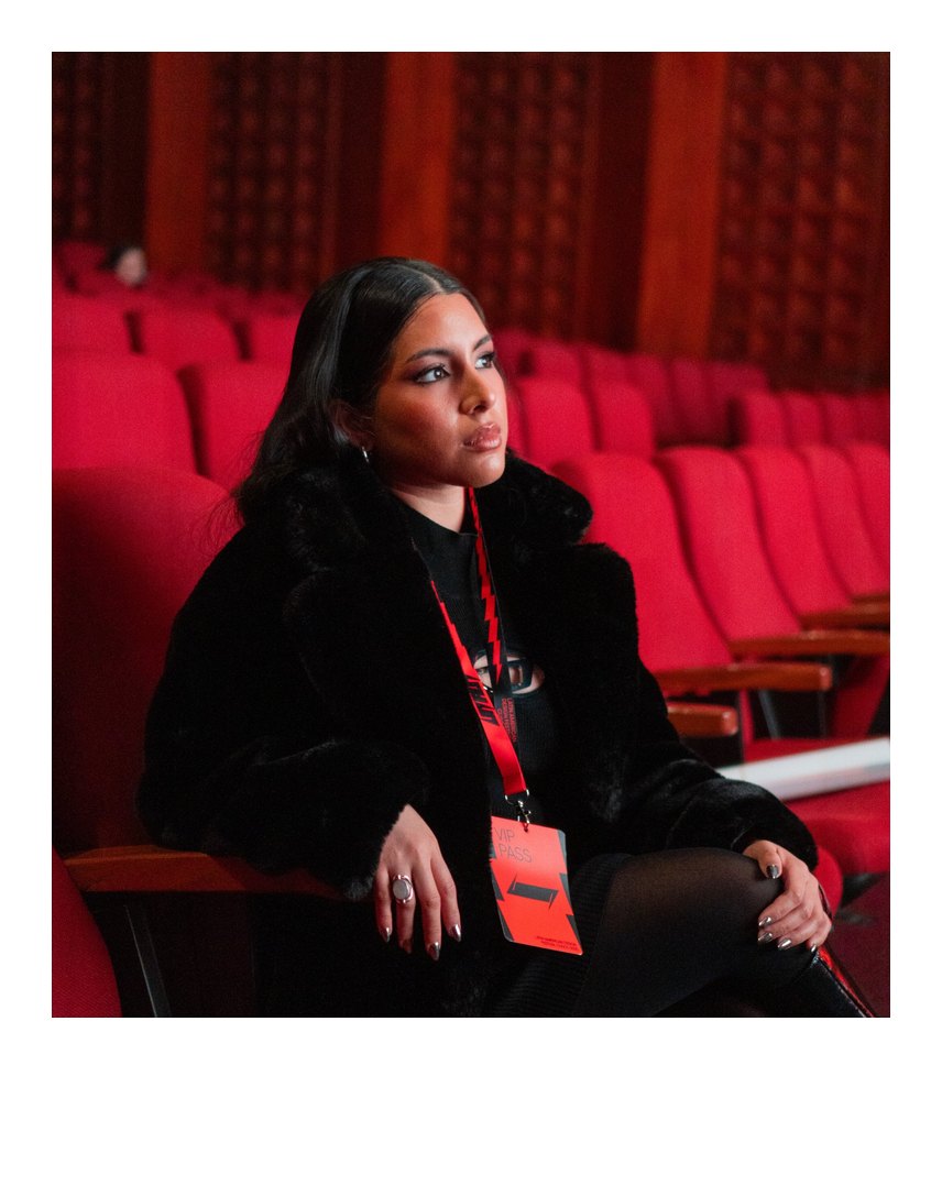 Marcela seated in a red auditorium